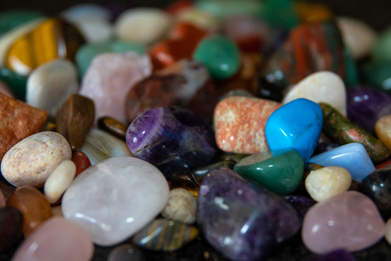 Speckled green aventurine tumbled stones scattered across a white marble surface