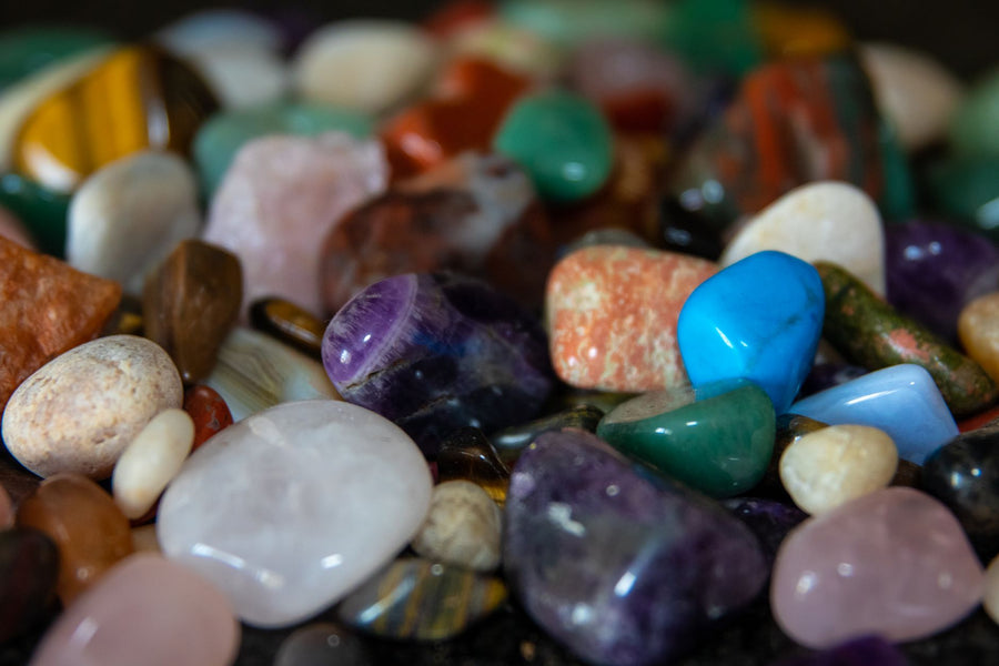 Speckled green aventurine tumbled stones scattered across a white marble surface