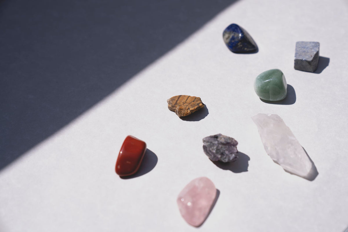 Lilac lepidolite and white howlite tumbled stones scattered on soft pale linen